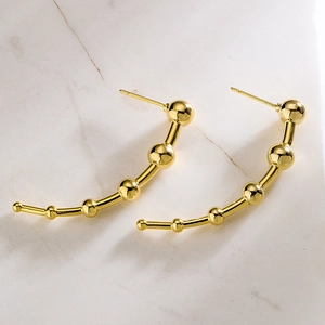 Irregular geometric gold-plated beaded stud earrings on a white marble surface