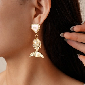 Detail of model wearing gold fish heart earrings with pink and white gemstones