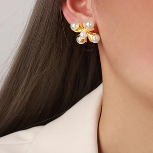 Elegant gold cross petal earrings with faux pearls worn by model in a side view profile
