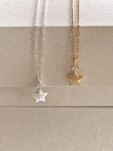 Detail of star pendant necklaces in gold and silver finish with zircon stone inlay