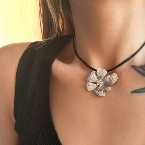 Close-up of 18k gold plated daisy flower necklace with zircons and black rope cord