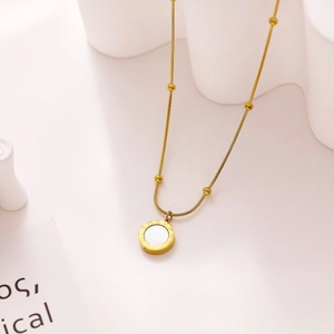 Close-up of golden necklace pendant with Roman numerals and white shell inlay detail