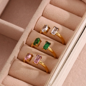 Three gold adjustable rings with white, green, and pink zircon stones in a jewelry box