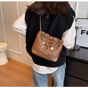 Brown quilted shoulder bag with gold chain and colorful heart charms on a model