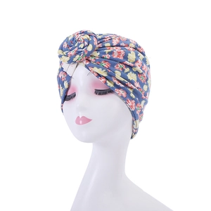 Detail of sky blue floral turban hat with vintage knot design and vibrant flower prints