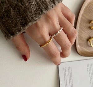Detail of twisted knot silver and gold rings worn on fingers with a minimalist aesthetic
