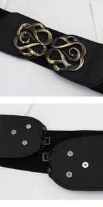 Detail of vintage bronze floral metal buckle and snap closure on black wide elastic belt