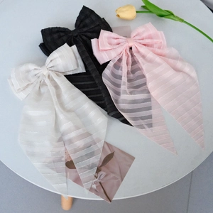 Detailed view of large striped fabric bow hair clips in white black and pink colors