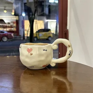 Irregular cream ceramic mug with hand-drawn pink heart and Love lettering on wooden table