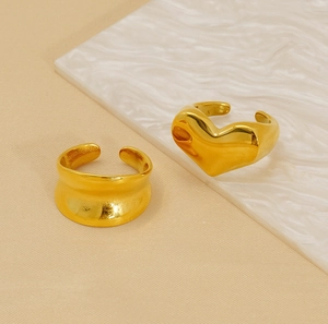 Detailed view of two gold titanium steel rings with wave texture and heart shape design