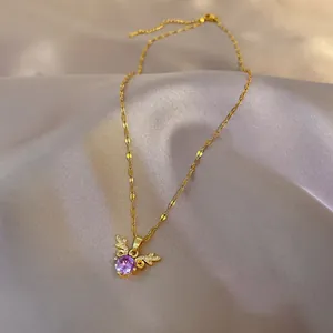 Detail of gold necklace with purple gemstone and zircon deer antlers on grey silk fabric