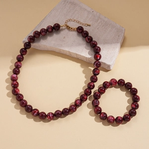 Detailed view of bohemian acrylic marbled beads necklace and bracelet on stone