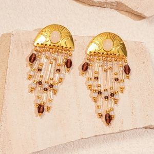 Detail of shell-shaped gold earrings with agate and crystal beaded fringe on stone