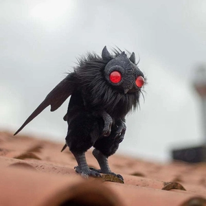 Εύκαμπτο βελούδινο Mothman μωρό με κόκκινα μάτια σε σκηνικό με κεραμιδένια στέγη