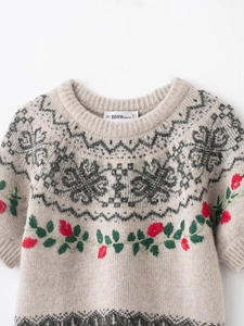 Detailed view of beige knit sweater featuring jacquard geometric patterns and rose embroidery