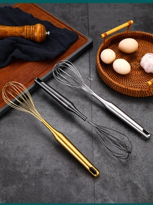 Close-up of three stainless steel whisks in gold black and silver on a kitchen counter