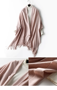 Close-up of pink knitted wool shawl showing fringe details and soft fabric texture