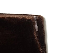 Macro view of dark brown velvet fabric showing invisible zipper craftsmanship detail