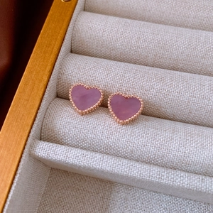 Macro shot of rose gold heart earrings with purple mother-of-pearl and beaded edges