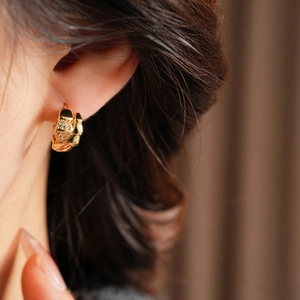 Detailed close-up of gold snake texture earrings with micro-inlaid zircon on model