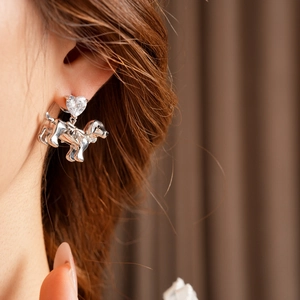 Close-up of silver dachshund earrings with heart-shaped cubic zirconia worn by a model