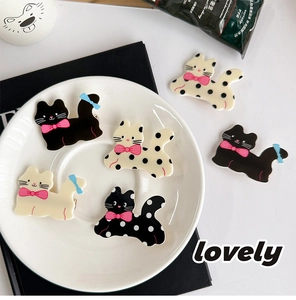 Close-up of colorful polka dot cat hair clips with decorative bows on a white tray