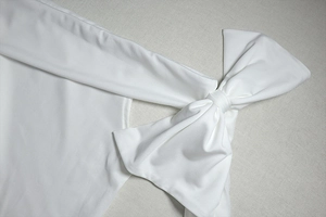 Détail d'une robe blanche élégante à épaules dénudées avec un grand nœud en tissu