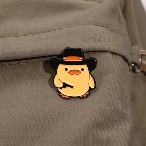 Niedliche gelbe Ente Emaille-Anstecknadel mit Cowboyhut und Pistole auf grünem Rucksack