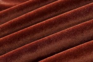 Detailed macro view of brown velvet fabric texture with soft glossy pleated ripples
