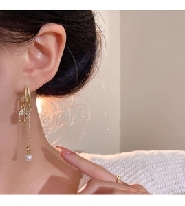Detail of long gold tassel earrings with pearls and rhinestones on a model's ear