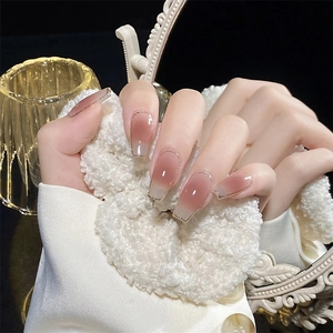 Detailed view of coffin-shaped gradient pink press-on nails with delicate gold glitter edges