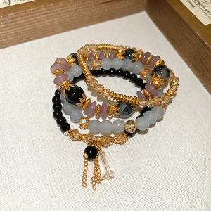 Detail of multi-layer beaded bracelets with vintage gold spacers and crystal tassel charm