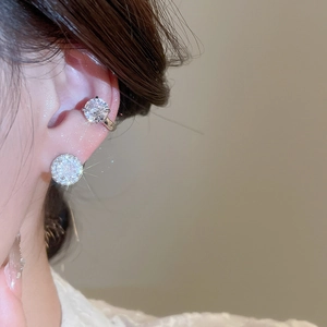 Close-up of sparkling zircon geometric round earrings and ear cuff on a female model