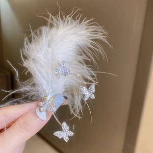 Detail view of silver bow ear cuff with white feathers, rhinestones and pearls