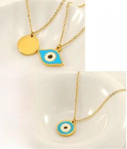 Detail of two gold stainless steel evil eye pendants with blue and black enamel finishes