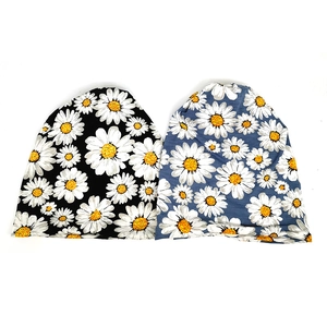 Detail view of black and grey slouchy beanies with all-over white daisy floral print