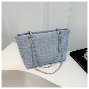 Detailed close-up of light blue textured plaid fabric and golden woven chain straps