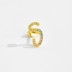 Macro detail of S-shaped S925 silver earring with colorful zircon stones in gold finish