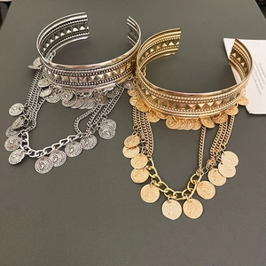 Detailed shot of bohemian style wide open cuffs with coin pendants and tassel fringe