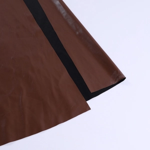 Dettaglio ravvicinato della cucitura tra ecopelle marrone scuro e tessuto elastico nero