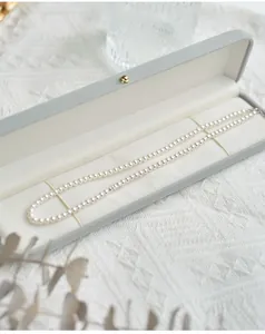 Elegant round white pearl necklace displayed in a luxury grey velvet jewelry gift box