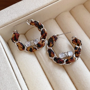 Détails de boucles d'oreilles C léopard avec zircons brillants sur velours blanc pur