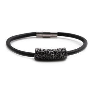 Detail of black leather bracelet with carved metal bead and magnetic clasp closure