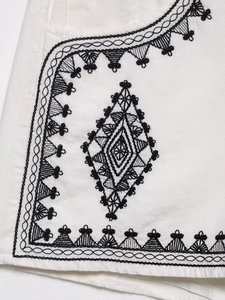 Detailed close-up of ethnic geometric embroidery on white cotton linen fabric
