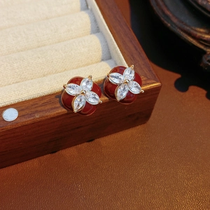 Close-up of red enamel flower earrings with sparkling zircons on a leather box