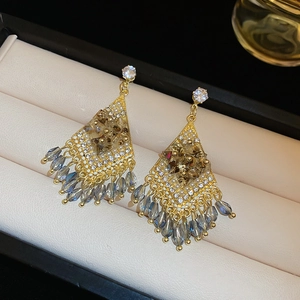 Macro shot of rhombus tassel earrings with amber crystals on a beige leather display