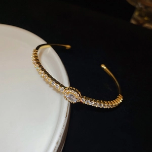 Detailed view of a gold-plated cuff bangle with an oval center stone and zircon pavé