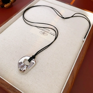 Detailed macro view of irregular silver geometric pendant with black cord on linen