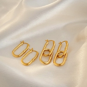 Close-up of gold U-shaped earrings on white silk featuring smooth polished metal finish