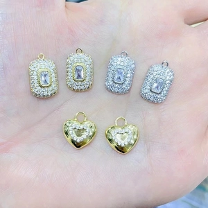 Detail of rectangular and heart pendants with full diamonds held in hand to show size